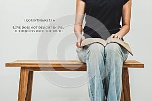 Casual young woman holds an open Bible 1 Corinthians 13:6 on her