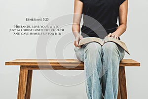 Casual young woman holds an open Bible Ephesians 5:25 on her lap