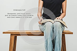 Casual young woman holds an open Bible Ephesians 5:25 on her lap photo