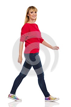Casual Young Woman Is Walking And Looking At Camera. Side View