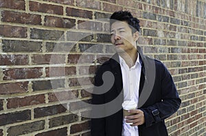 Casually dressed Asian man standing with coffee