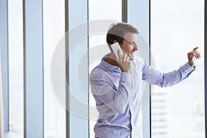 Casually Dressed Businessman Using Mobile Phone In Office