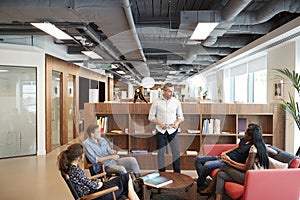 Casually Dressed Businessmen And Businesswomen Having Informal Meeting In Modern Office