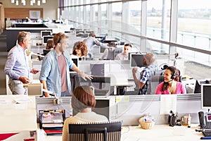 Casually dressed colleagues talking in an open plan office