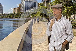 Casually dressed, a mature man takes a walk alongside the waterfront downtown