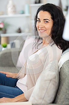 casually dressed middle-aged woman sitting on sofa