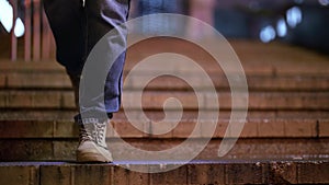 casually dressed woman is walking in city in evening or night, closeup of feet on stairs