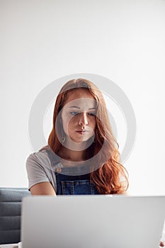 Casually Dressed Young Businesswoman Working On Laptop At Desk In Modern Workplace