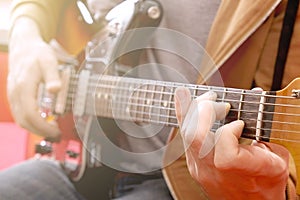 Casually dressed young man with guitar playing songs in the room at home. Online guitar lessons concept. Male guitarist practicing