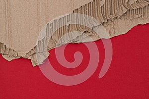 Casually torn sheet of kraft cardboard  paper texture and relief on red background