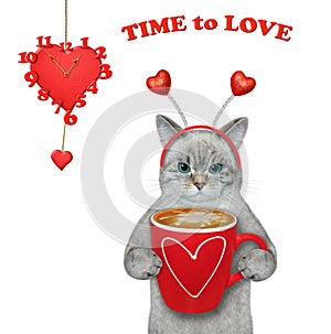 Cat ashen holds coffee near heart shaped clock