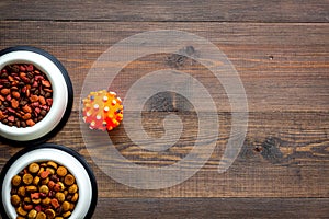 Cat and dog food in bowl on dark wooden background top view space for text