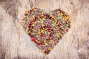 Cat food on wooden background. Cat food in the shape of heart. Top view