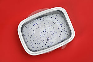 Cat litter tray with filler on red background, top view