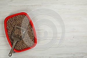 Cat litter tray with filler and scoop on white wooden floor, top view. Space for text