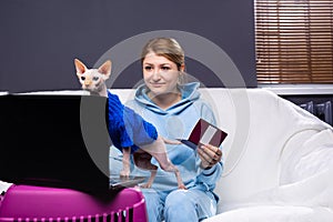 Cat owners woman with pet passport in front of laptop pc at home. Veterinary animal digital identification, modern technology. Pet