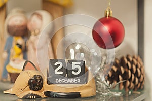 Cat-shaped wooden calendar surrounded by the nativity and other Christmas decorations shows the date of December 25th