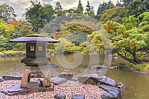 Cat sheltering from the autumn rain under a Japanese stone lantern of Kyufurukawa Park.