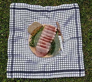 Cat sniffing ham on a wooden plate