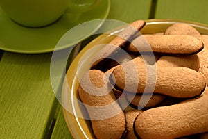 Cat tongues biscuits with chocolate on a plate near cup and saucer.