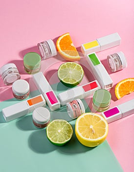 Catalog photo of goods for manicure. Bottles of nail polish with fresh fruits on pink background