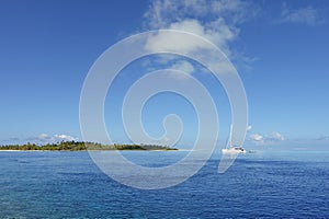 A catamaran anchors in a lagoon under a blue sky off the island of Fakarava in French Polynesia photo