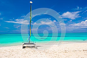 Catamaran with colorful sail on caribbean beach