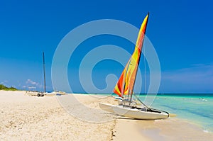 Catamaran with colorful sails on a tropical beach in Cuba