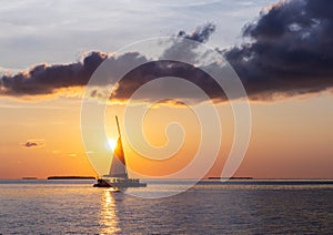 Catamaran sailboat at sunset.