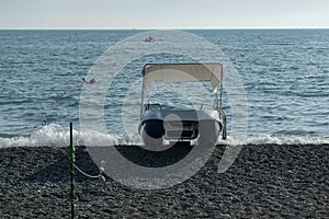 Catamaran on the seashore. Waves of the sea surf on the stone beach.