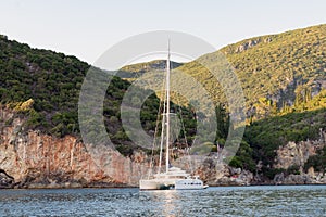 Catamaran yacht boat waiting parked in rocky bay sea sunset