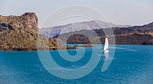 Catamaran yaht enters the bay of Thira Santorini. Enigmatic island silhouette on the horizon in the sea