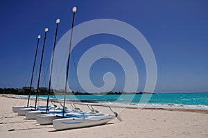 Rental Catamarans parked on a white beach. photo