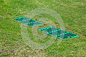 Catch basin grate drainage on the lawn with green grass septic tank.