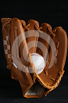 Catcher`s mitt and baseball ball on black background. Sports game