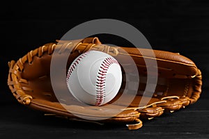 Catcher`s mitt and baseball ball on black background. Sports game