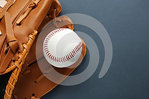 Catcher`s mitt and baseball ball on dark background, top view with space for text. Sports game