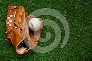 Catcher's mitt and baseball ball on green grass, top view with space for text. Sports game