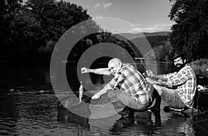 Catching fish. Father and mature son fisherman fishing with a fishing rod on river.
