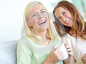 Catching up over coffee. Two attractive young women smiling while having coffee together.