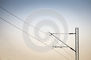 Catenary power overhead line of a railroad track, supplying electricity for trains, with a pylon pillar in the background