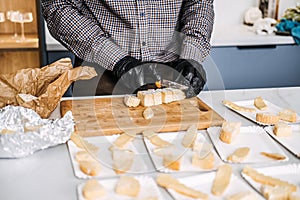 Caterer Preparing Cheese Platters for an Event. Professional caterer arranges various types of cheese on plates, wearing