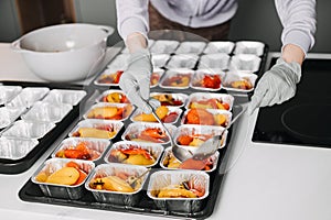 Caterer in a professional kitchen preparing individual servings of roasted vegetables, showcasing meticulous food
