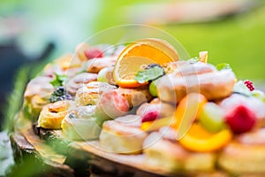 Catering buffet food outdoor. Cakes colorful fresh fruits berries oranges grapes and herb decorations