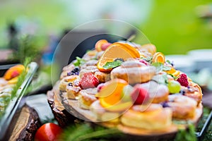 Catering buffet food outdoor. Cakes colorful fresh fruits berries oranges grapes and herb decorations