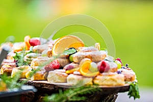 Catering buffet food outdoor. Cakes colorful fresh fruits berries oranges grapes and herb decorations