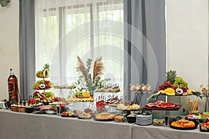 catering buffet table with snacks and appetizers. Set of varios fruits and berries. Decorative vase photo