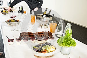 Catering Desserts on Buffet Table with Man Serving Red Wine in the Background