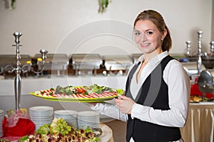 Catering service employee posing with tray for buffett