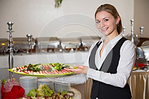 Catering service employee posing with tray for buffett